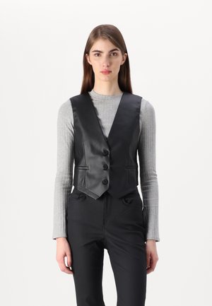 Zwarte neplederen vest met een aangesloten ontwerp, drie knopen en twee voorzakken, gedragen over een lichtgrijs geribd longsleeve shirt.