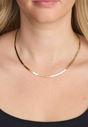 Kullatooni kaelakee sujuva, kõverdatud disainiga; lame, poleeritud pind; asetub paljale kaelale musta topi kohale.