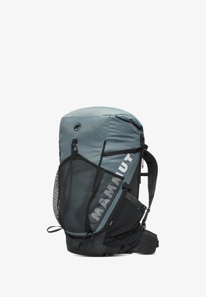 Mochila azul-gris con bolsillo lateral de malla, correas ajustables y acentos negros. Presenta una superficie texturizada y un logotipo en la parte frontal.