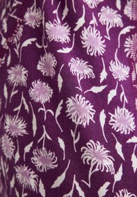 Fioletowa tkanina z różowym i białym wzorem kwiatowym, zawierająca stylizowane kwiaty chryzantemy oraz rozrzucone kształty liści.