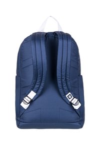Mochila azul marino con correas de hombro acolchadas, un asa superior y acentos blancos. Presenta un diseño elegante y minimalista con una forma estructurada.