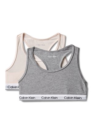 Dwa sportowe biustonosze Calvin Klein z racerbackiem, jeden w jasnobeżowym kolorze, drugi w szarym, oba z markowymi elastycznymi pasami u dołu.