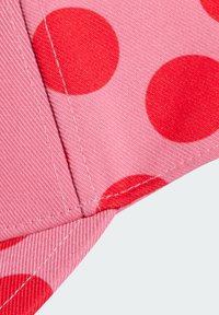 Tessuto rosa con grandi pois rossi. La superficie presenta una trama testurizzata, e le cuciture sono visibili lungo i bordi.