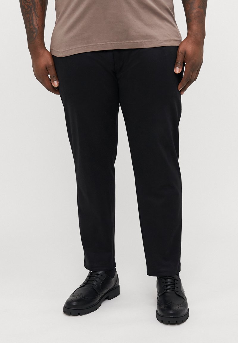 Pantaloni negri cu croi slim, având o textură netedă și un design minimal. Asortați cu pantofi negri de dress și o cămașă gri.