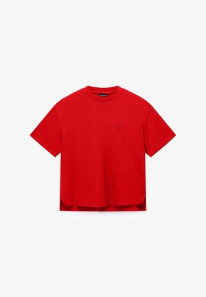 Jednobarevné červené tričko s krátkými rukávy, kulatým výstřihem, malým logem na hrudi a rozparky na bocích u lemu.