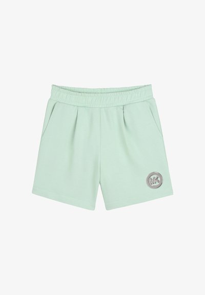 Shorts verts clairs avec taille élastique, poches latérales et un logo circulaire argenté sur la jambe gauche.