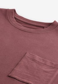 T-shirt in cotone malva con collo rotondo, dotato di una tasca a toppa sul lato sinistro e una texture liscia e morbida.