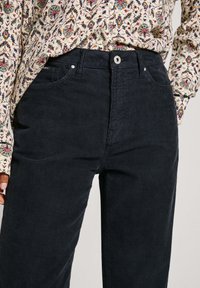 Pantalones de pana azul oscuro con un patrón acanalado texturizado, cierre frontal con botón, dos bolsillos y un diseño ajustado.