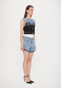 Tumedast heledaks ülemise osa denim vest, mis sisaldab hõbedasi nööpe ja taskuid. Kombineeritud heledate denim lühikeste pükste ja mustade kontsadega.