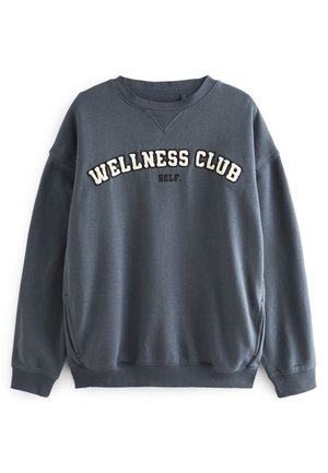 Tamsiai mėlynas džemperis su balta ir juoda siuvinėta "WELLNESS CLUB" ir "SELF." užrašu, vidine apykakle ir elastingomis rankovėmis. Minkšta medžiaga.