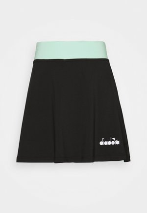 Falda atlética negra con una cintura de un suave tono verde menta, hecha de material elástico. Presenta un logo blanco impreso en el lado inferior.