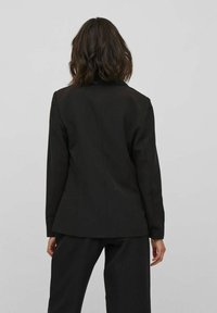 Černý přizpůsobený/blazer s fitted střihem, klopeným límečkem a dlouhými rukávy. Hladká textura, navržený pro strukturovaný vzhled.