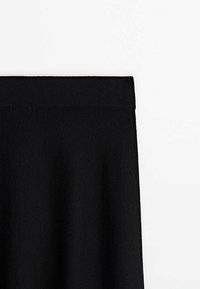 Jupe tricotée noire avec une large ceinture élastique, présentée sur un fond blanc.
