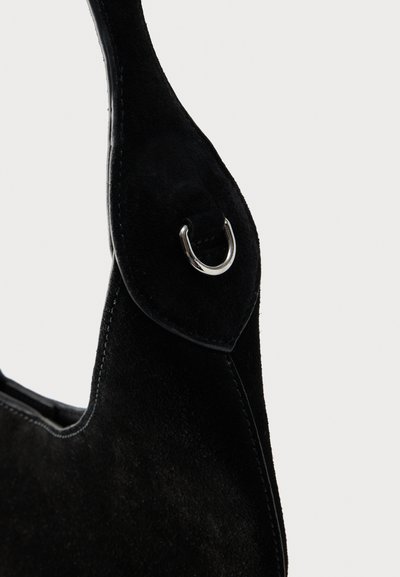 Μαύρο λουράκι τσάντας από σουέντ με ασημένιο μεταλλικό κρίκο σε σχήμα D και λεπτομερείς ραφές σε απλό ανοιχτό φόντο.