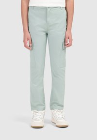 Lichtgroene cargobroek van zachte stof, met twee zijzakken en een rechte snit. Gecombineerd met witte sneakers.
