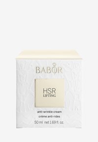 Emballage en cube blanc avec texture en relief, accents dorés et une étiquette carrée indiquant "HSR LIFTING crème anti-rides," taille de 50 ml.