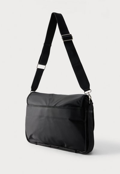 Μαύρη ορθογώνια τσάντα messenger με ρυθμιζόμενο ιμάντα ώμου και μεταλλικά κούμπωματα, απεικονισμένη σε απλό φωτεινό φόντο.