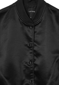 Veste bomber en satin noir avec col côtelé et fermetures à boutons, taille petite étiquetée "Caliope" sur l'étiquette intérieure.