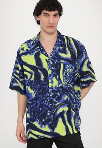 Trumpas rankovėmis mygtukų marškiniai su ryškiai mėlynu ir neoniniu žaliu gyvūnų raštu. Pagaminti iš lengvos medžiagos, su laisvu siluetu.