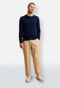 Maglione a maglia navy, pantaloni beige chiaro e scarpe color crema. Design slim-fit; texture liscia, stile casual con scollatura a girocollo e maniche lunghe.