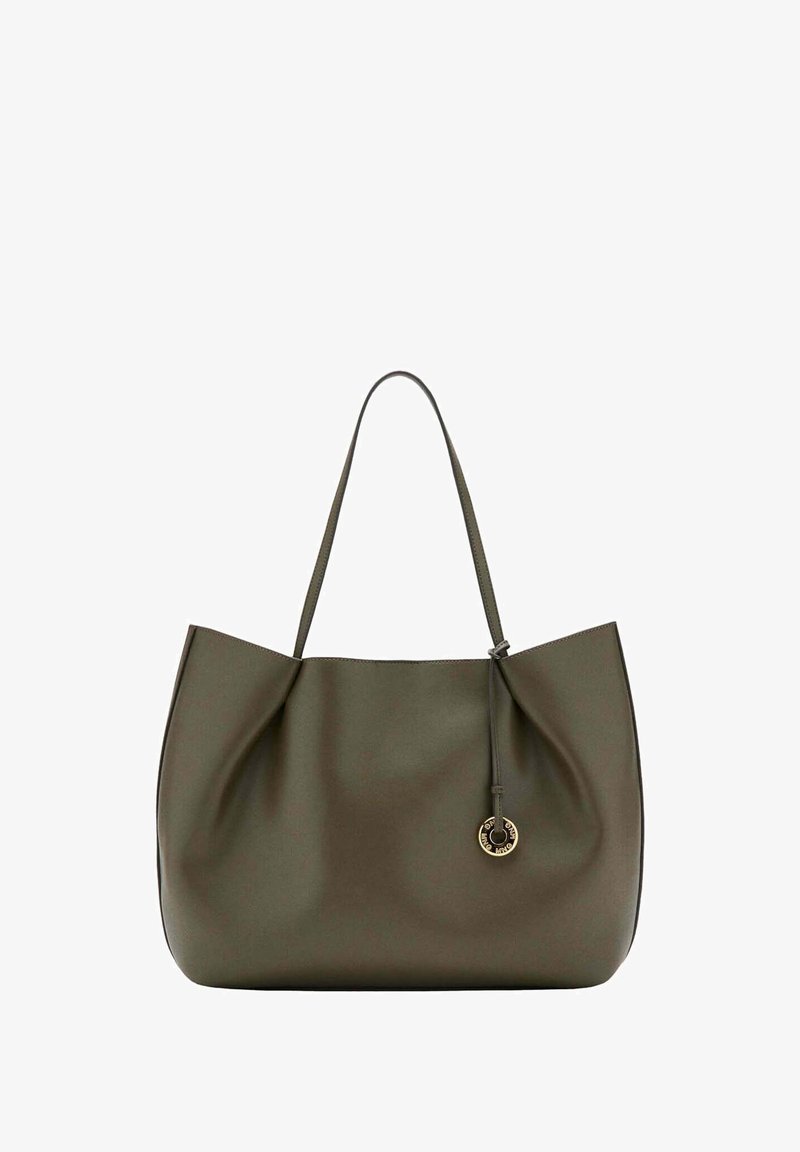 Sac cabas en cuir vert olive avec des bretelles fines et un petit charme décoratif rond doré suspendu à un cordon en cuir.
