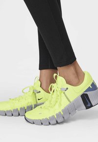 Scarpe Nike giallo neon con tomaia strutturata, suola grigia e accenti blu. Presentano lacci, rete traspirante e un design della suola segmentata.