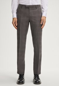 Grau karierte Anzughose mit tailliertem Schnitt, mit glatter Textur und klaren Linien. Kombiniert mit schwarzen Leder-Schuhe.