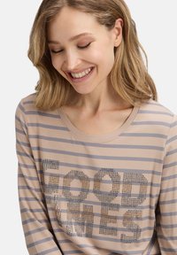 Beige Langarmhemd mit grauen Streifen, verziert mit "GOOD TIMES" aus Strasssteinen. Weicher Stoff mit rundem Ausschnitt.