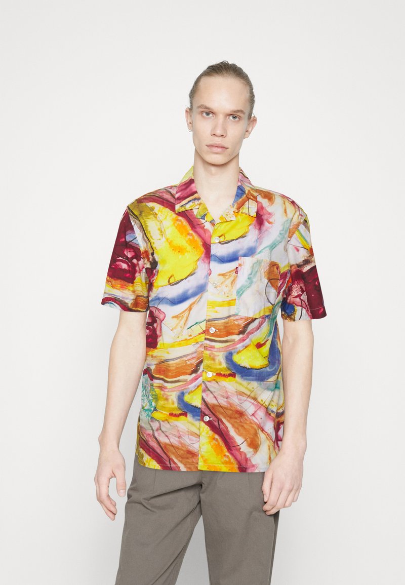 Cămașă cu mânecă scurtă, din țesătură ușoară, având un model abstract vibrant în culori galben, roșu și albastru, cu un buzunar pe piept.