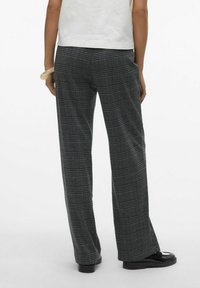 Pantalons à carreaux noirs et gris avec une coupe à jambes larges. Dotés d'une taille haute et d'un tissu lisse et texturé. Pas de matériel visible.