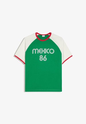 Zielona koszulka z białymi rękawami i czerwonym obszyciem, z napisem „MEXICO 86” w stylu retro w białej czcionce z przodu.