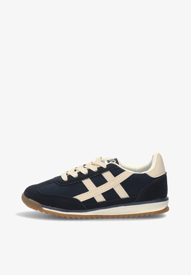 Zapatilla deportiva azul marino con acentos beige, que cuenta con una parte superior de gamuza y malla, cierre de cordones y una suela de goma texturizada.