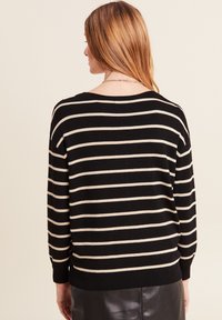 Schwarzer und cremefarbener gestreifter Pullover mit langen Ärmeln, lockerer Passform, gerippten Bündchen und Saum. Weiches Strickmaterial mit weitem Ausschnitt.