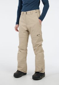 Beige waterdichte skibroek met een rechte pasvorm, twee zijzakken en een logo op het linkerpijp. De stof lijkt soepel en duurzaam.