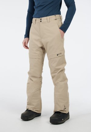 Beige waterdichte skibroek met een rechte pasvorm, twee zijzakken en een logo op het linkerpijp. De stof lijkt soepel en duurzaam.