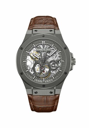 Skeletton automatisk ur med et metallic grått hus og et brunt tekstureret læderrem. Viser synlige gear og guld accenter på urskiven.