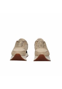 Sneaker in suede beige con linguetta imbottita, lacci testurizzati e tallone nero a contrasto. Suola in gomma con motivo a battistrada geometrico.