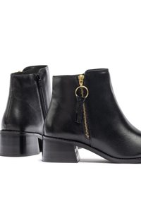 Botas de tobillo de cuero negro con punta redonda, tacón bajo en bloque y cremalleras laterales con herrajes dorados y un acento en forma de bucle.
