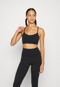 Zwarte sportbeha en hoge taille leggings gemaakt van zachte, elastische stof, met dunne bandjes en minimale naden voor comfort en ondersteuning.