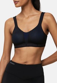 Brassière de sport noire avec tissu en maille respirante aux accents bleus, larges bretelles et une bande discrète de marque en bas.