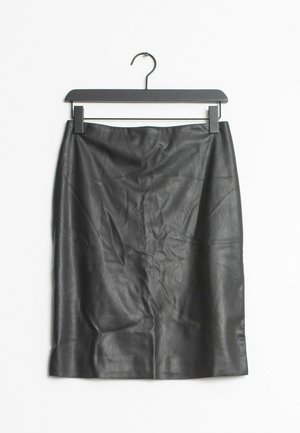Jupe en cuir noire longueur genoux suspendue sur un cintre noir sur fond blanc.