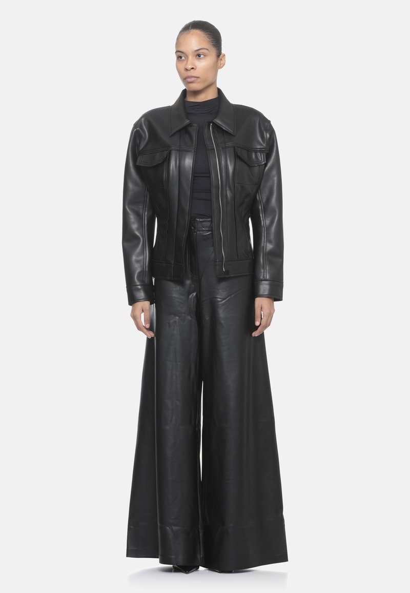 Giacca in pelle nera con ampi rever, chiusura con zip e due tasche frontali abbinata a pantaloni in pelle a gamba ampia. Texture liscia.
