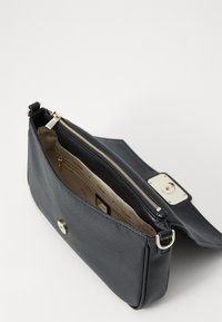 Bolso de mano de cuero negro texturizado con cierre superior con cremallera, herrajes dorados y cierre de clic en el frente. El interior presenta un forro beige claro.