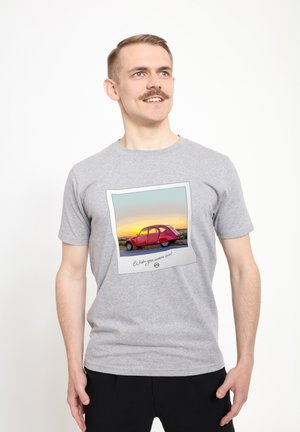 Grå T-shirt med korte ærmer, der har et grafisk motiv af en rød vintage bil i en polaroidramme med en solnedgang i baggrunden og en tekst nedenfor.