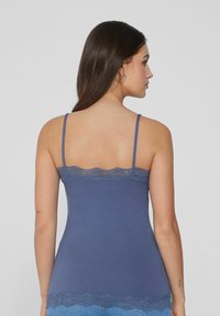 Niebieska koszulka na ramiączkach z cienkimi paskami i delikatnymi koronkowymi wykończeniami na górnej i dolnej krawędzi, wykonana z miękkiego, elastycznego materiału.