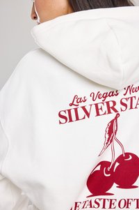 White hoodie featuring burgundy graphics of cherries and text “Las Vegas New Silver Star. A Taste Of.” Cozy fabric with a relaxed fit.