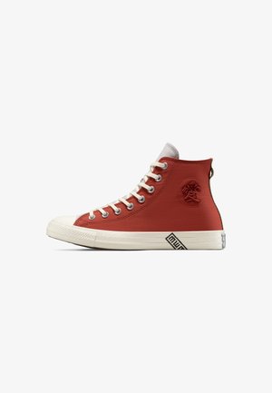 Hoher roter Sneaker mit weißen Schnürsenkeln, weißer Gummisohle und einem runden Emblem mit einem eingeprägten asiatischen Zeichen an der Seite.