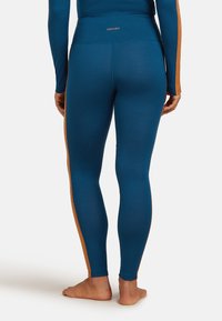 Blå leggings som är tillverkade av ett slätt, elastiskt tyg har en bred midjeresår och en kontrasterande orange sidremsa längs de yttre sömmarna.