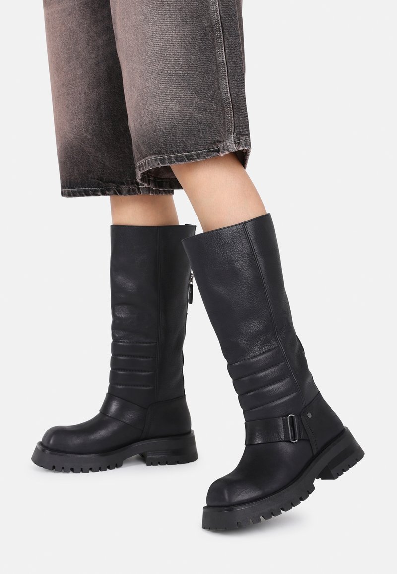 Black leather knee-high boots featuring a pleated design, round toe, durable sole, and ankle strap with a buckle detail.