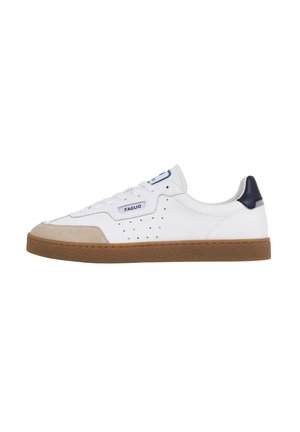 Witte sneaker met een suède neuskap, geperforeerde zijkanten en een marineblauwe hielaccent. Voorzien van witte veters en een bruine rubberen zool.